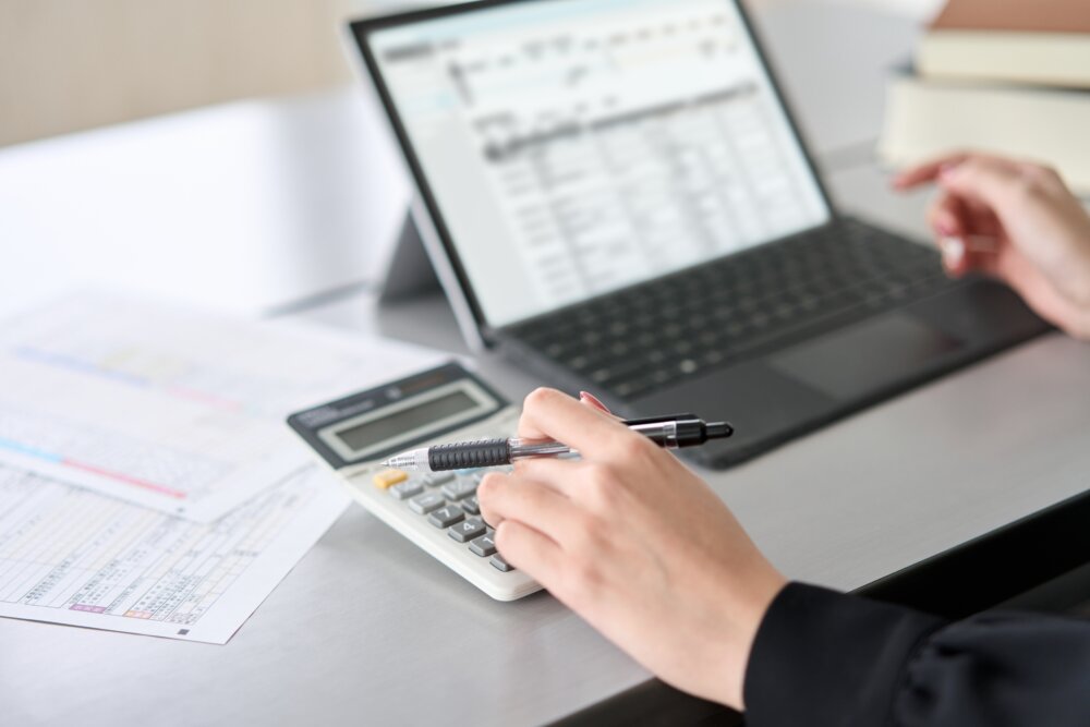 Asian,Woman,Using,Accounting,Software,And,Calculator